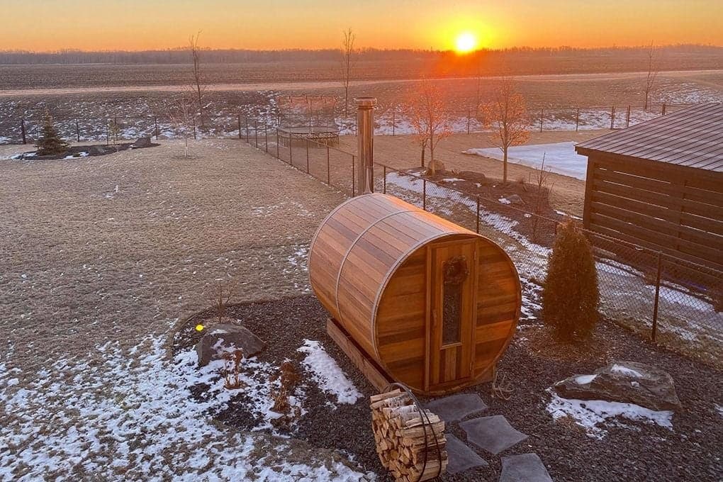 Cedar barrel sauna on an Alberta property at golden-hour sunset